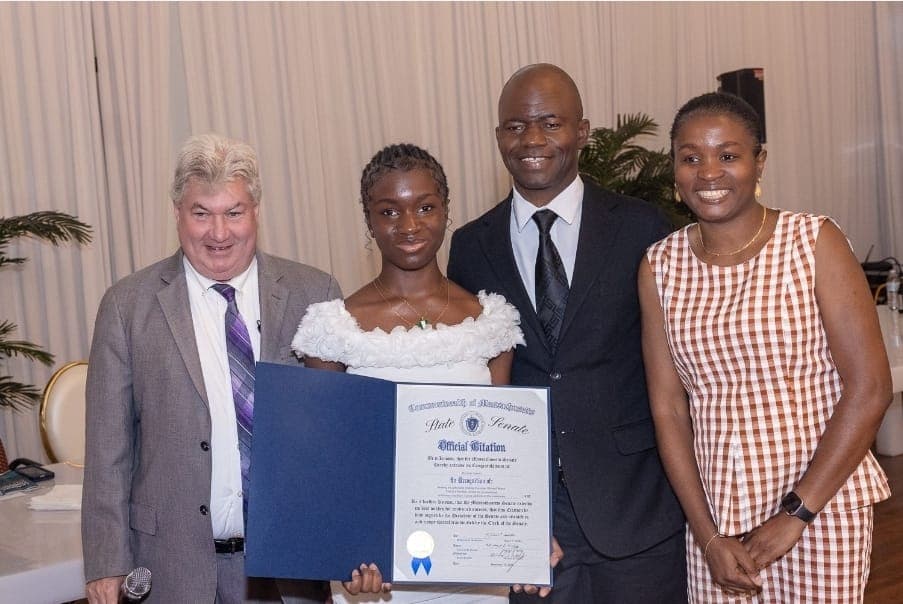 A young author holds her Official Citation with Senator Michael Brady, Charles Awodu, and family.