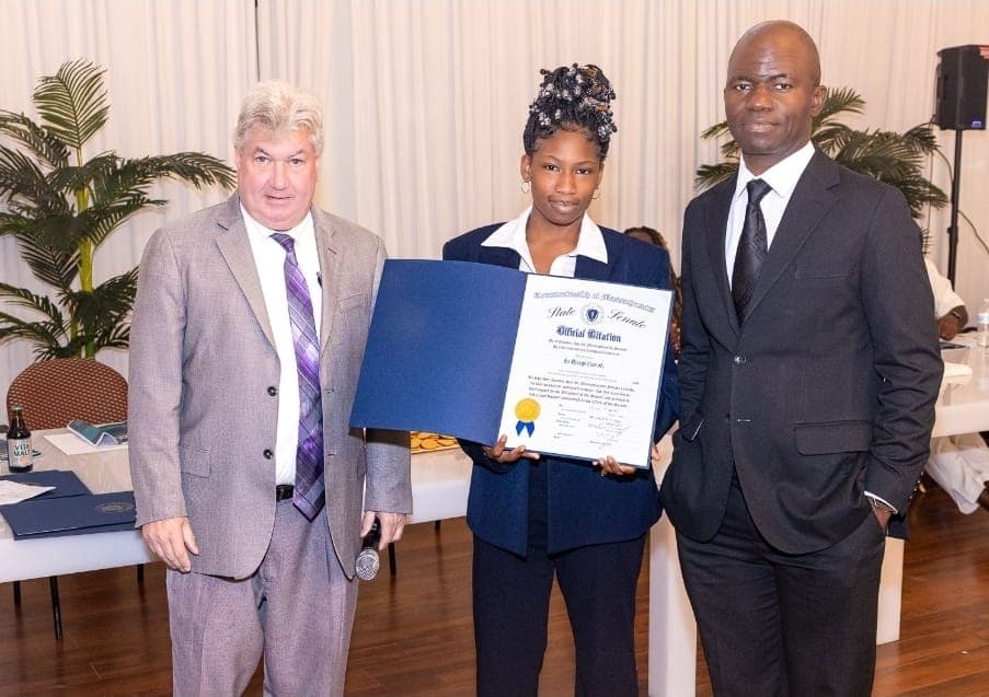 A young leader holds her Official Citation with Senator Michael Brady and Charles Awodu.