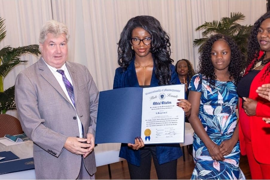 A young leader holds her Official Citation with Senator Michael Brady and a younger guest.