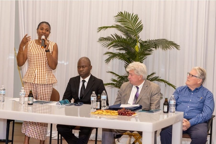 A guest speaks at the head table with Charles Awodu and Senator Michael Brady.